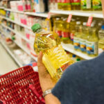 Caucasian housewife shopping for vegetable oil in a supermarket alley